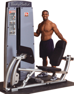 Man standing beside a leg press machine.