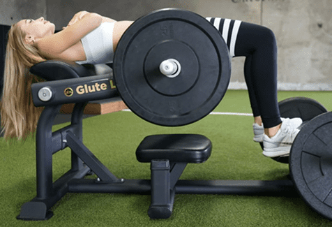Woman exercising on a leg press machine in a gym.