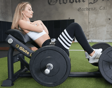 Woman exercising on a leg press machine in a gym.