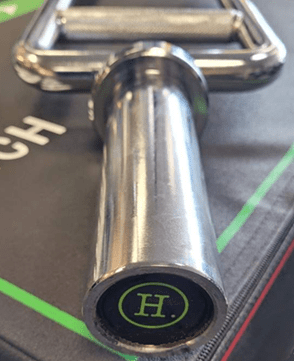 Close-up of a metal barbell handle with an 'H' logo.
