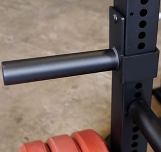 Close-up of a barbell and weight rack in a gym.