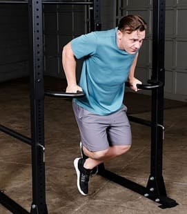 Man doing dips exercise on parallel bars indoors.