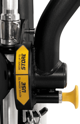 Close-up of a black machine part with a yellow safety label and a yellow knob.